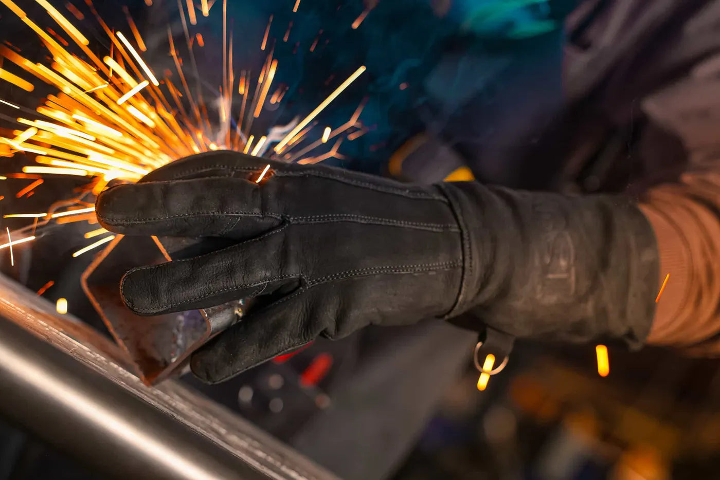 Close-up of black-thread leather welding glove in action, gripping metal as sparks fly during grinding or welding work Rated 4.70 – Black