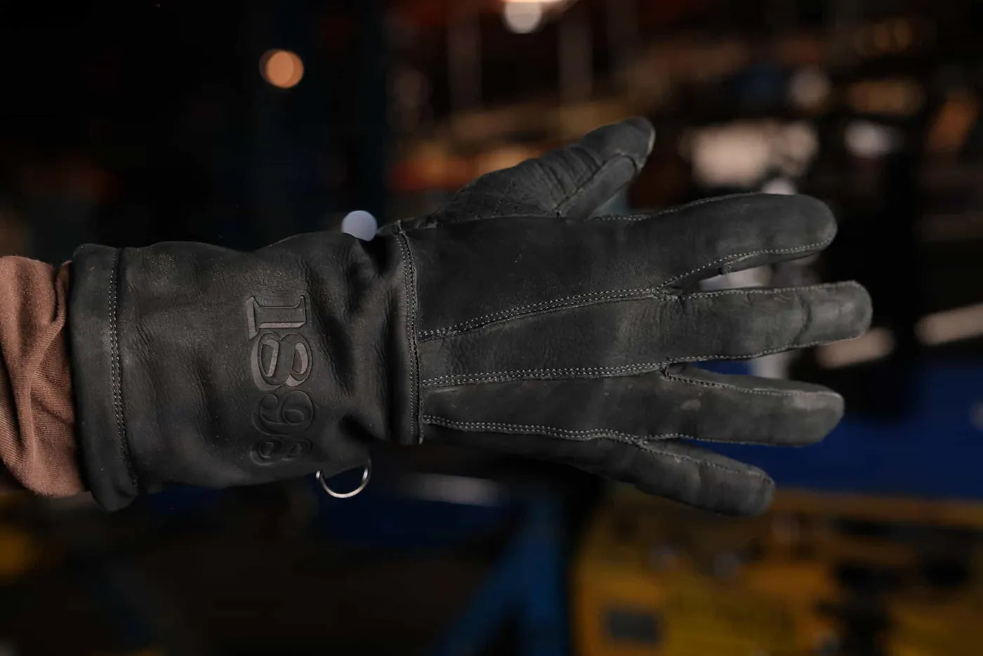 Close up of black thread leather work glove with “1898” embossed on the wrist and metal ring attachment, highlighting craftsmanship and rugged utility Rated 4.70 – Black