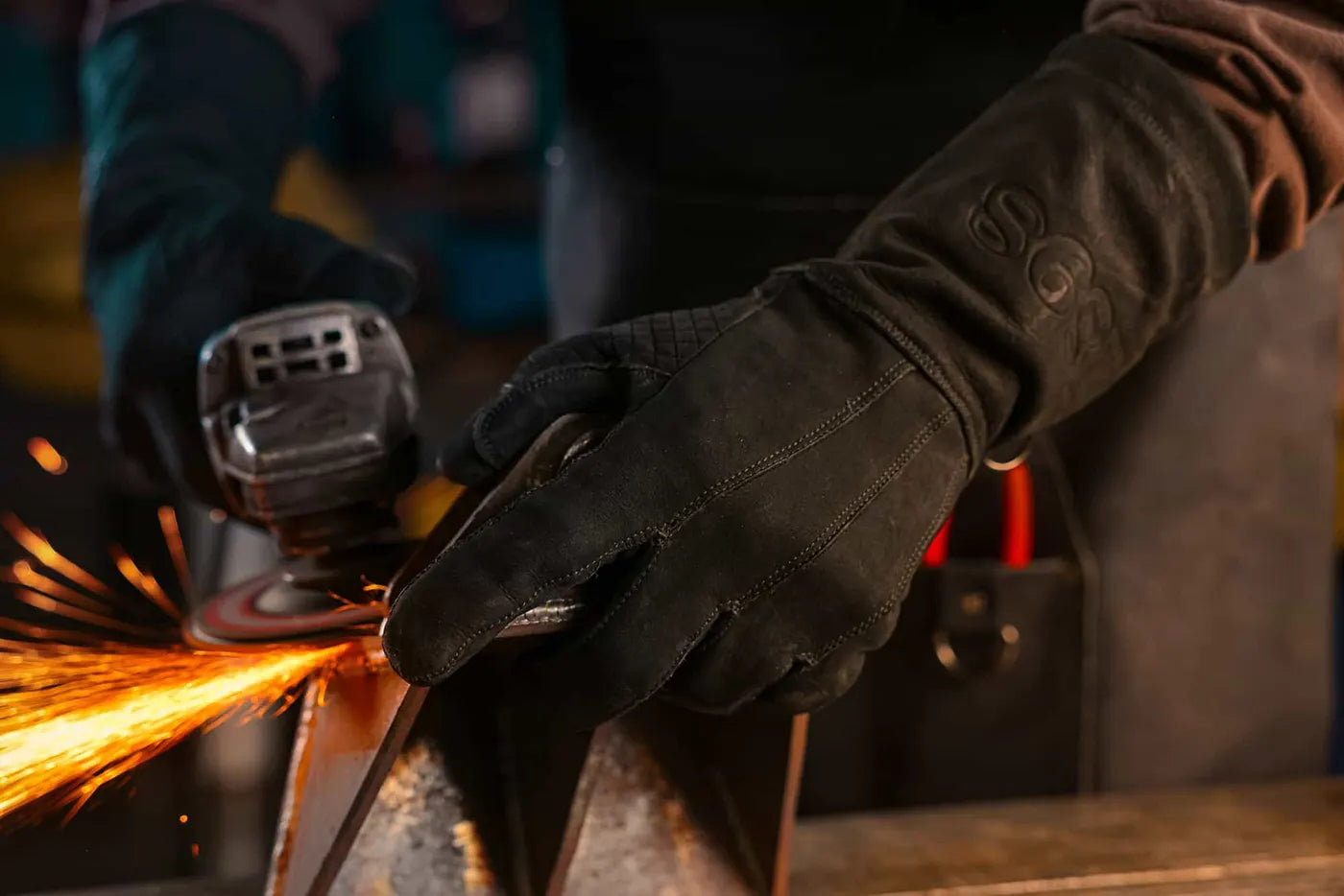 Black-thread leather work gloves are in use while grinding metal with an angle grinder, sparks flying in a high-intensity workshop setting. Rated 4.70 – Black