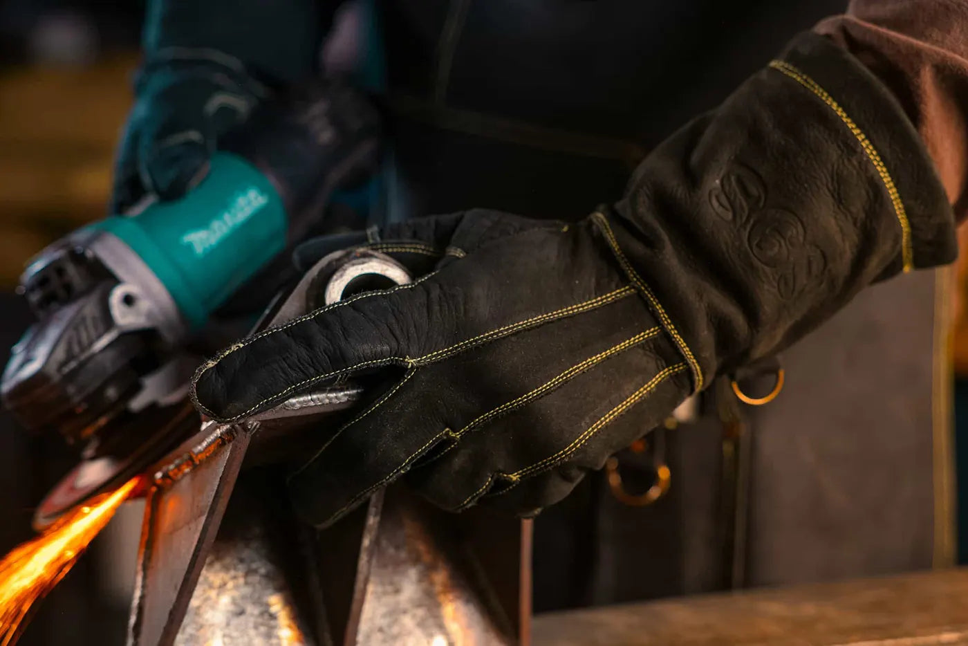 Gold-thread leather work gloves with “SGS” embossing in use while operating a Makita angle grinder, sparks flying during metal cutting – Rated 4.70 – Gold