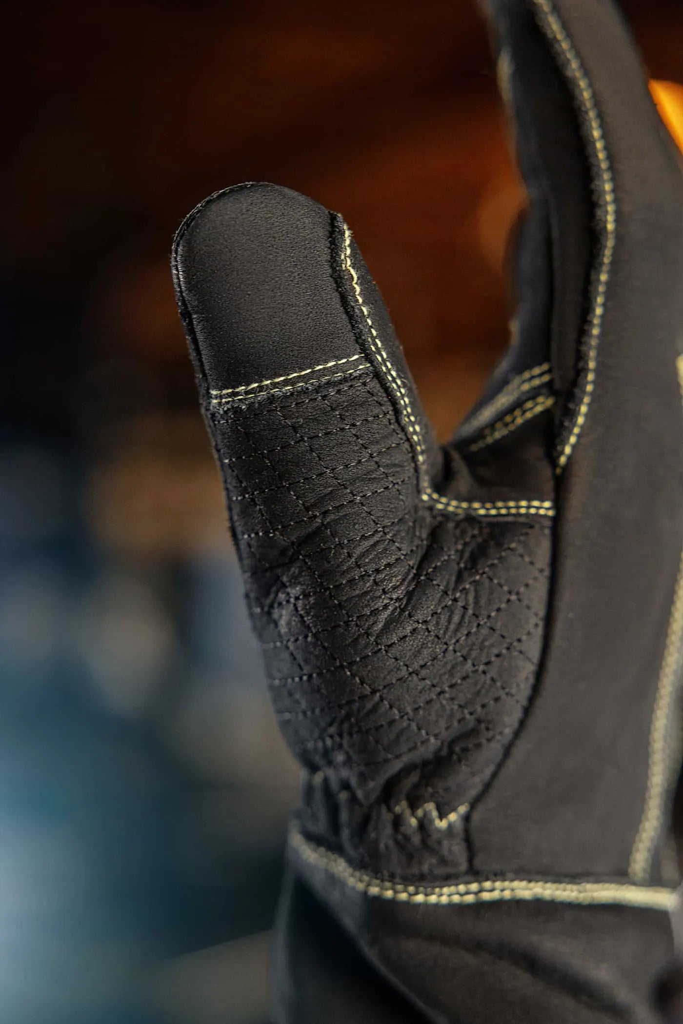 Close-up of gold-thread leather work glove showing reinforced thumb stitching and textured leather surface, highlighting precision craftsmanship and durability Rated 4.70 – Gold
