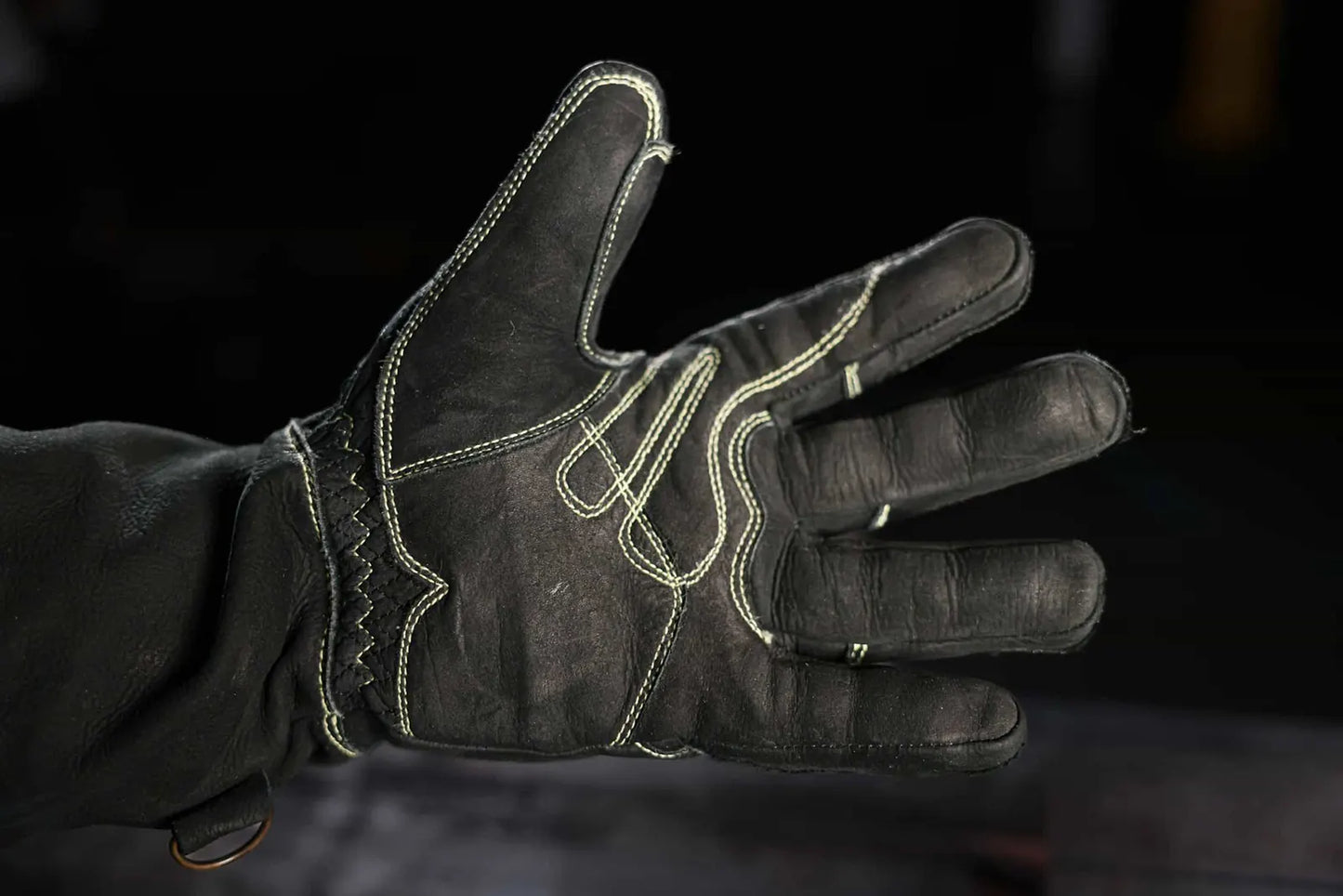 Close-up of leather glove with light-colored stitching on the palm and fingers, worn on a hand with fingers spread, highlighting contrast stitching, craftsmanship, and durability Rated 4.70 – Gold