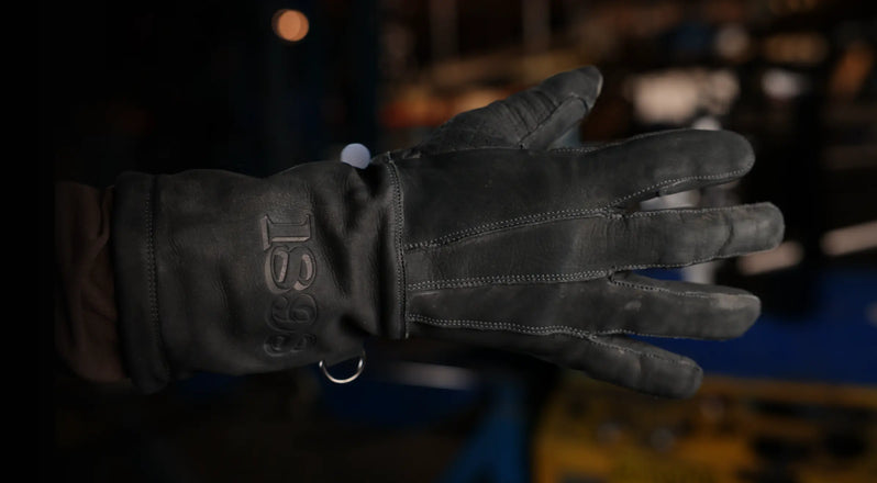 Close-up of leather glove with stitched detail and “1898” logo embossed on the wrist, framed for mobile view in an industrial setting – Rated 4.70
