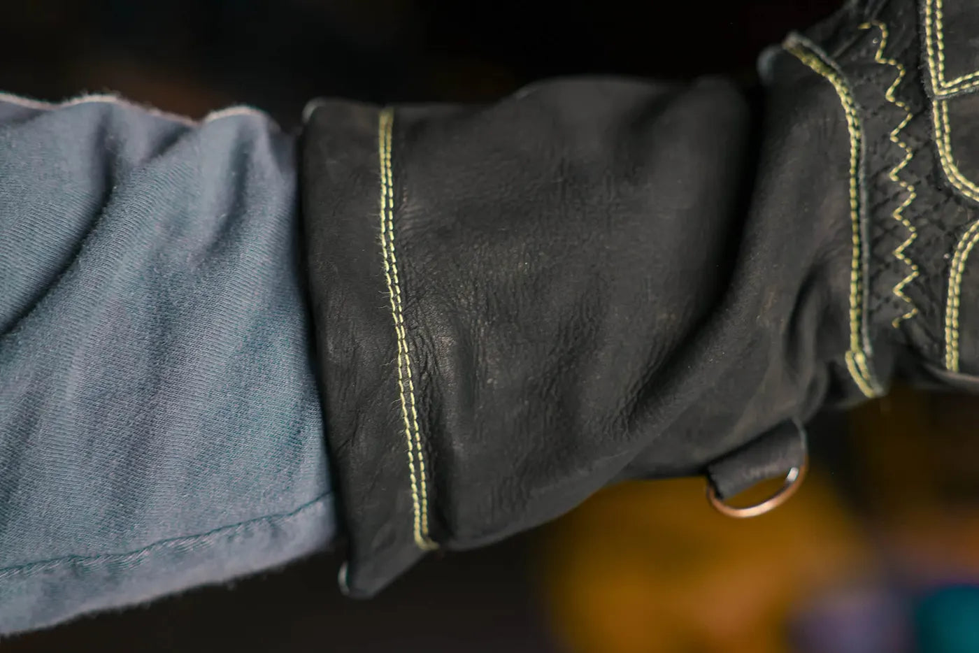 Extreme close up of yellow-thread leather work glove showing fine stitching and textured leather surface near the seam, highlighting craftsmanship and durability Rated 4.70 – Gold