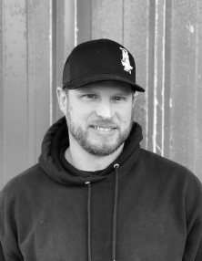 Black and white portrait of metal artist Jesse Purdom in a cap and hoodie