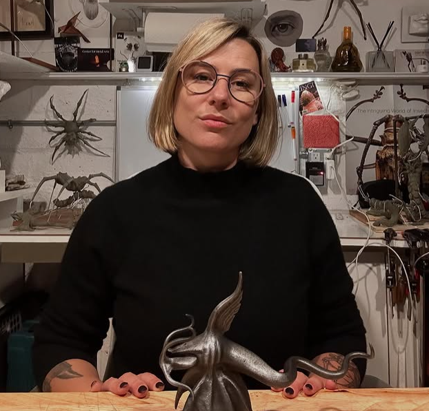 Metal artist Leah Aripotch with a steel squid sculpture and insect sculptures in her studio