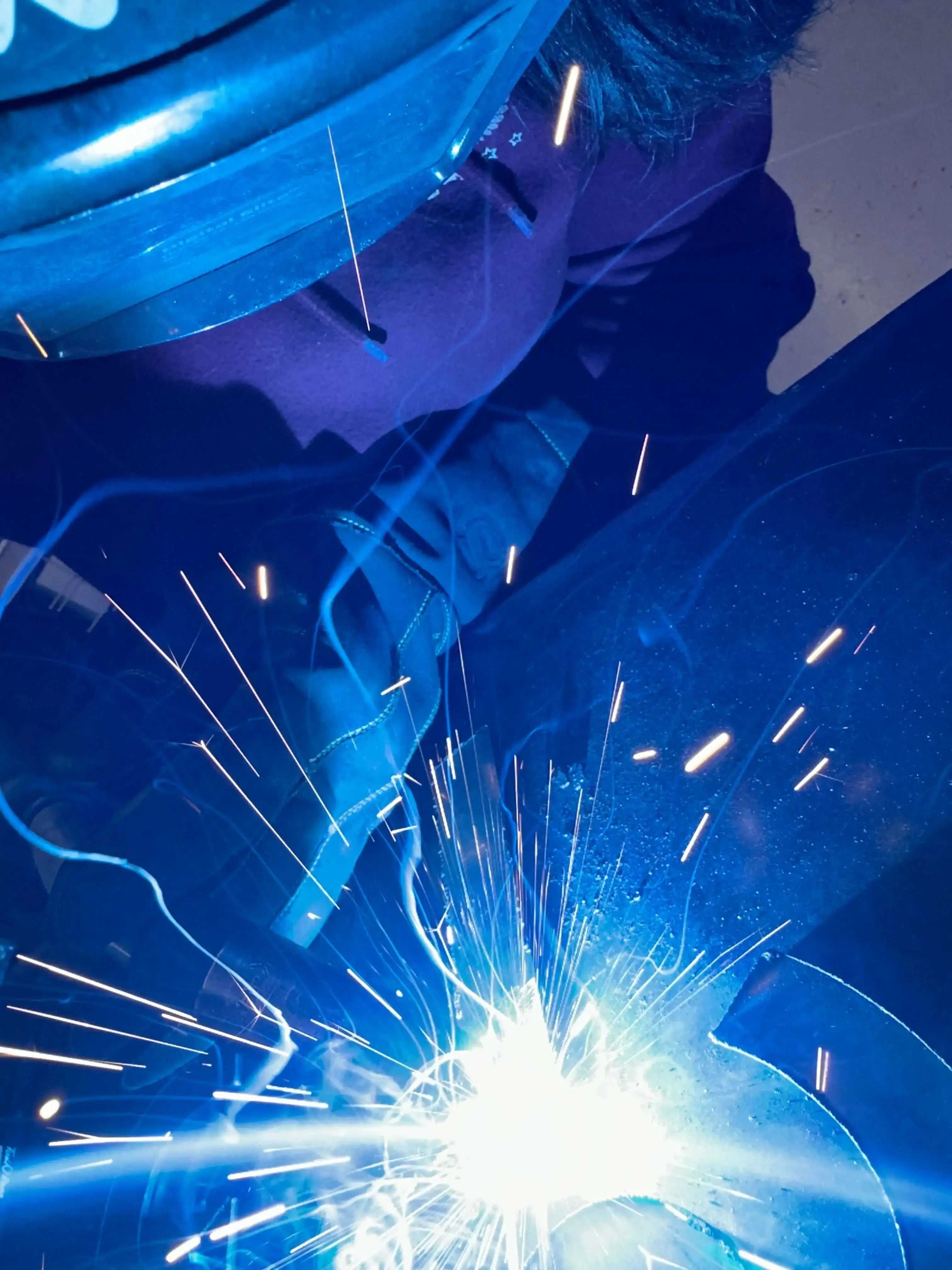 Utah State student welding with bright sparks and intense light while wearing 1898 Leather gloves — premium 4.7-star rated protection for high-heat work

