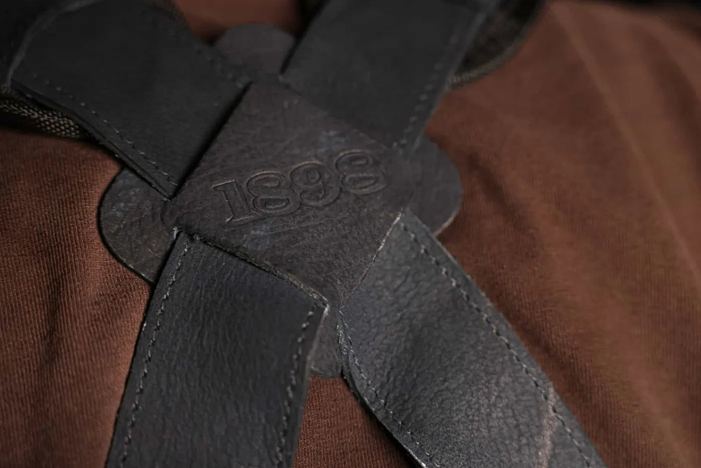 Back view of 1898 Leather welding apron black thread with shoulder crossover straps forming an X and 1898 logo at the intersection durable, premium apron rated 4.85 stars - Black