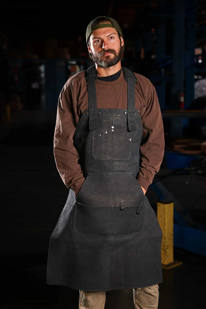 Model wearing 1898 heavy duty black leather welding apron with black thread stitching in front view – Black