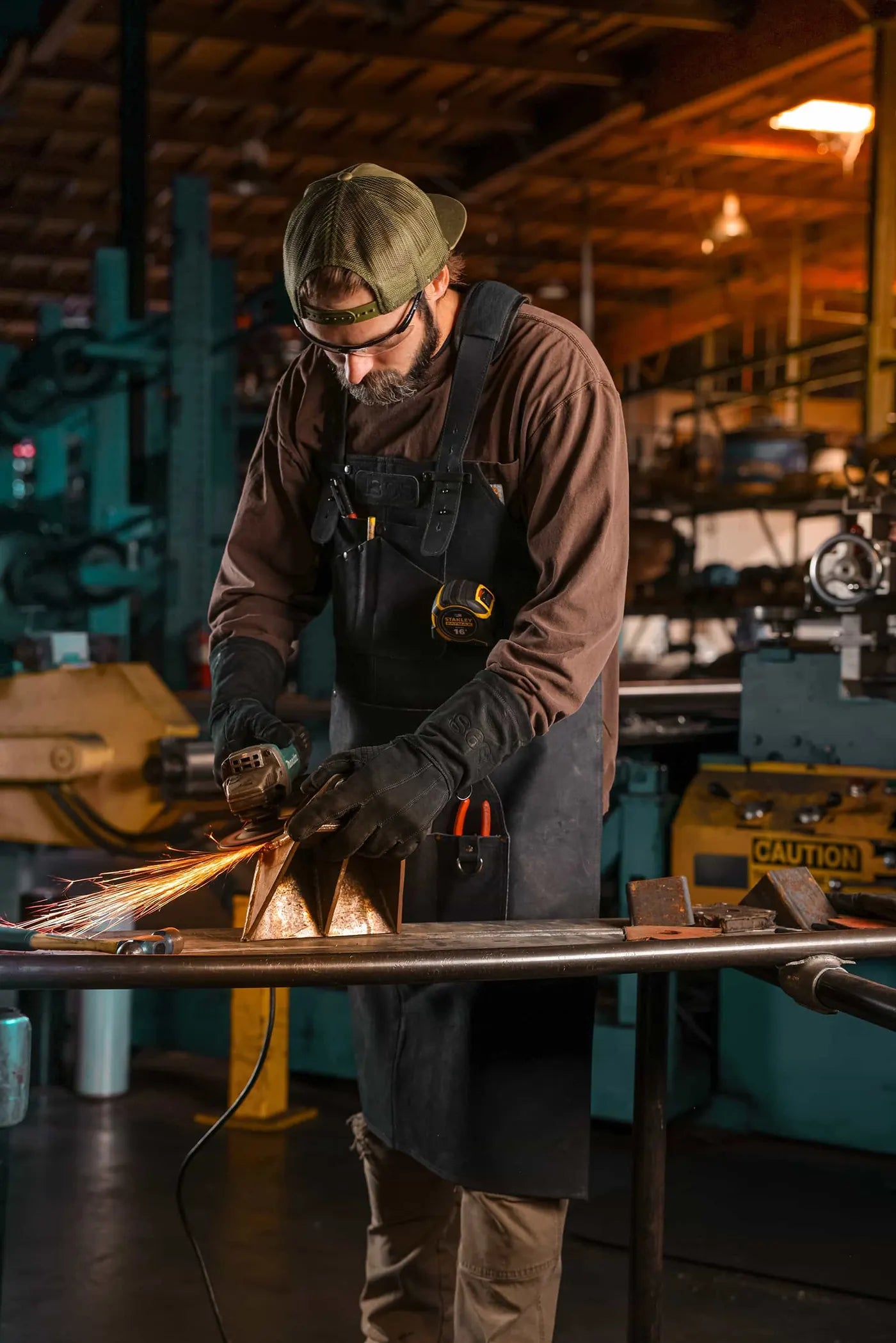 Worker welding metal while wearing 1898 heavy duty leather apron and gloves with black thread stitching and reinforced protection – Black