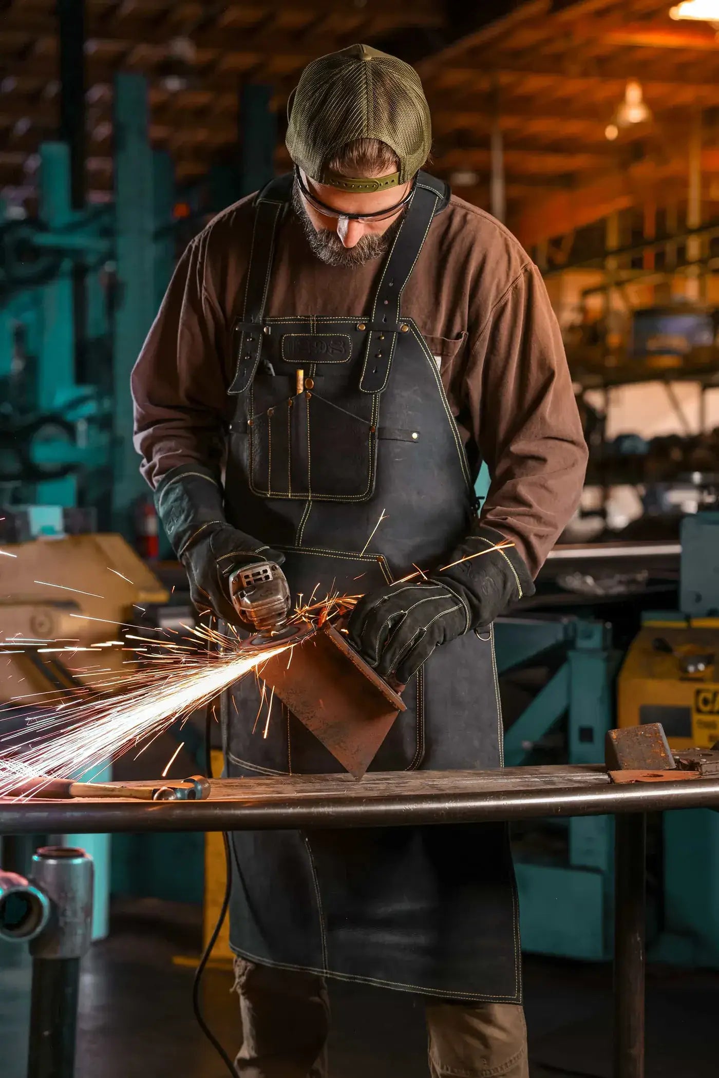 Worker welding metal while wearing 1898 heavy duty leather apron and gloves with gold contrast stitching and reinforced protection – Gold