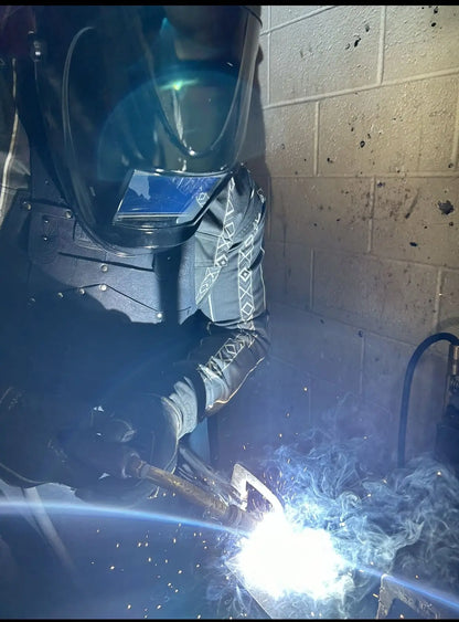 Black leather work apron with black stitching worn by a welder in full gear, actively welding metal with bright arc light and sparks flying — showcasing heat resistance, craftsmanship, and real-world durability – Rated 4.85 – Black
