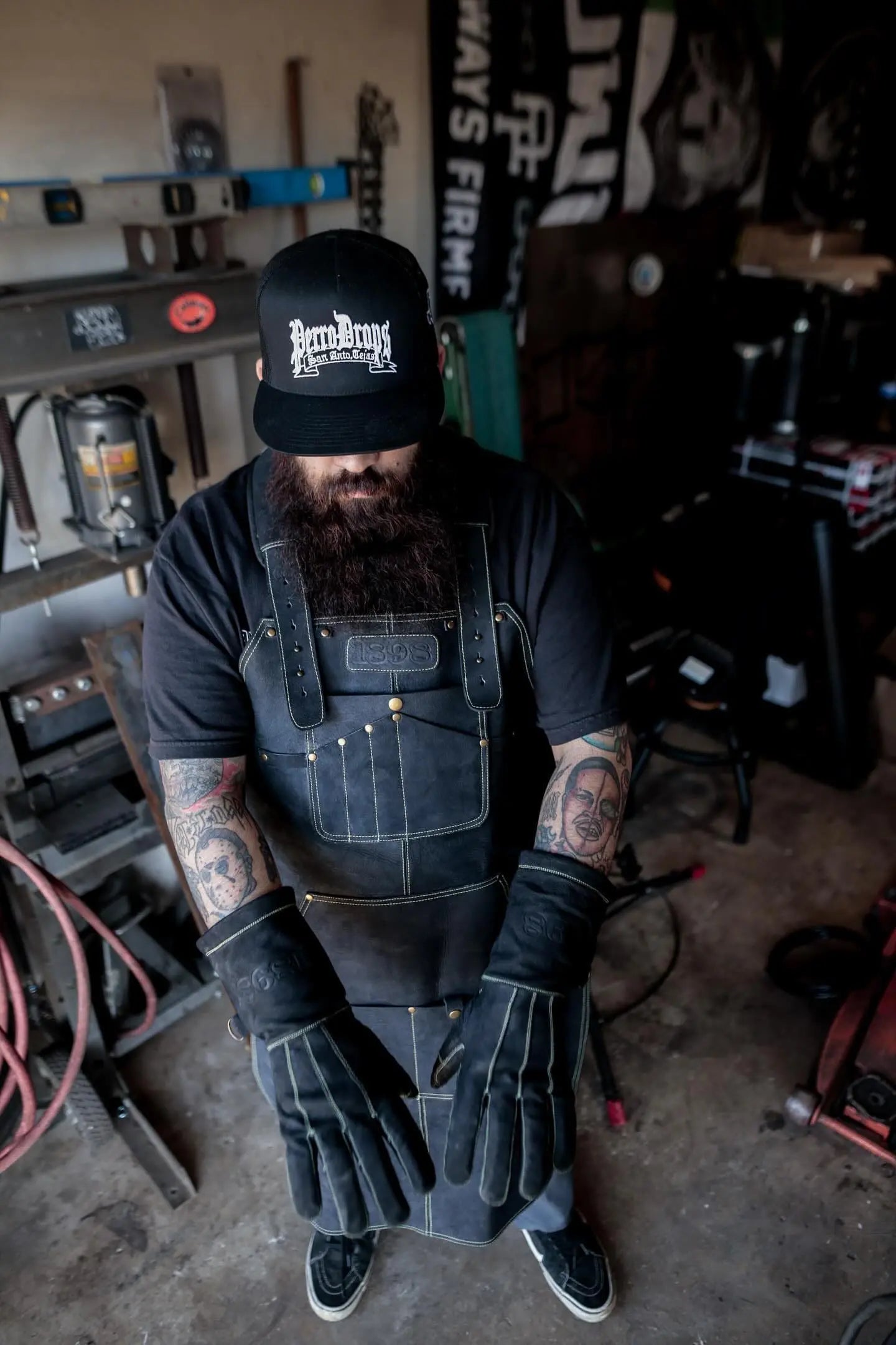 Person wearing a leather work apron with golden thread stitching and full welding gear, actively welding with blue arc light and sparks flying — highlighting protection, craftsmanship, and durability for industrial work – Rated 4.85 – Gold